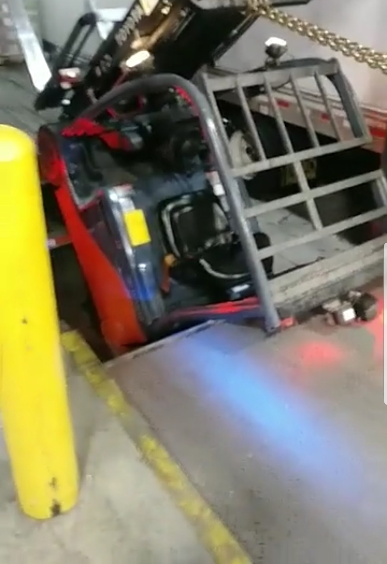 Forklift dropped at a dock edge with chassis wedged near a trailer ramp