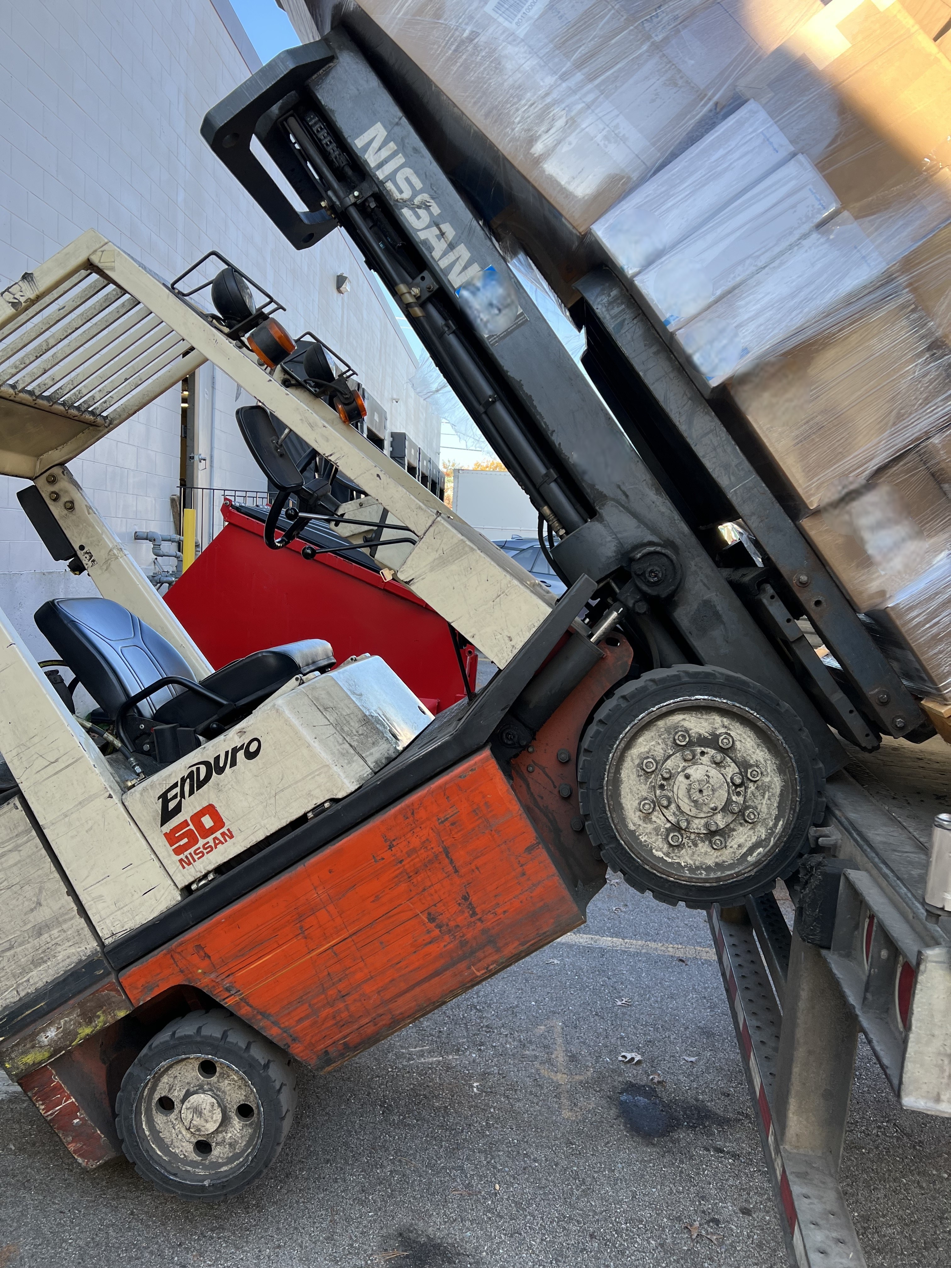 Forklift pitched forward while unloading a trailer with palletized cargo